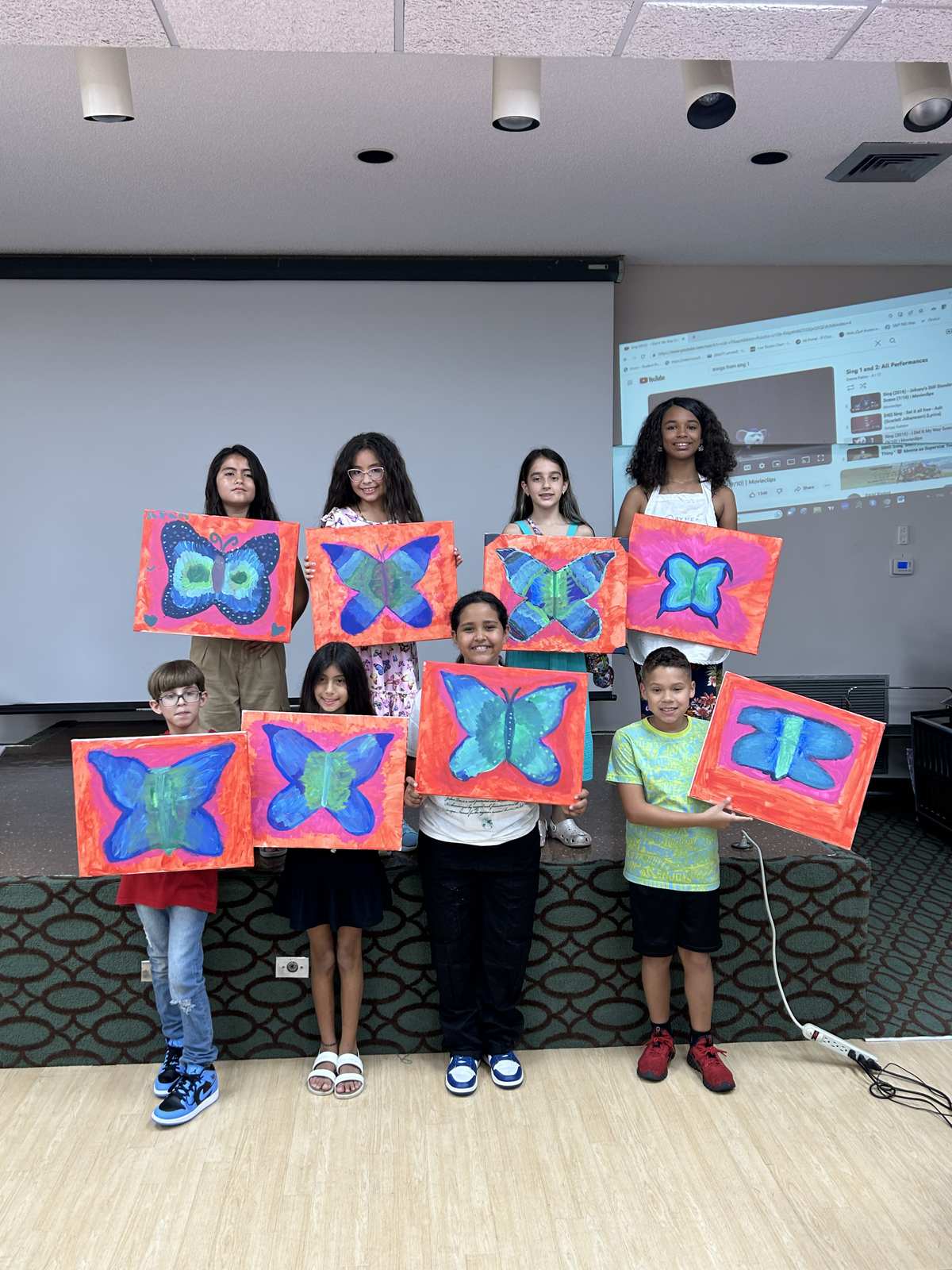 Group of students holding up the butterfly paintings they made